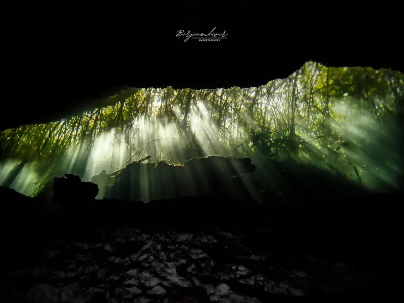 Rayons de soleil perçant l'eau d'une grotte sous-marine sombre