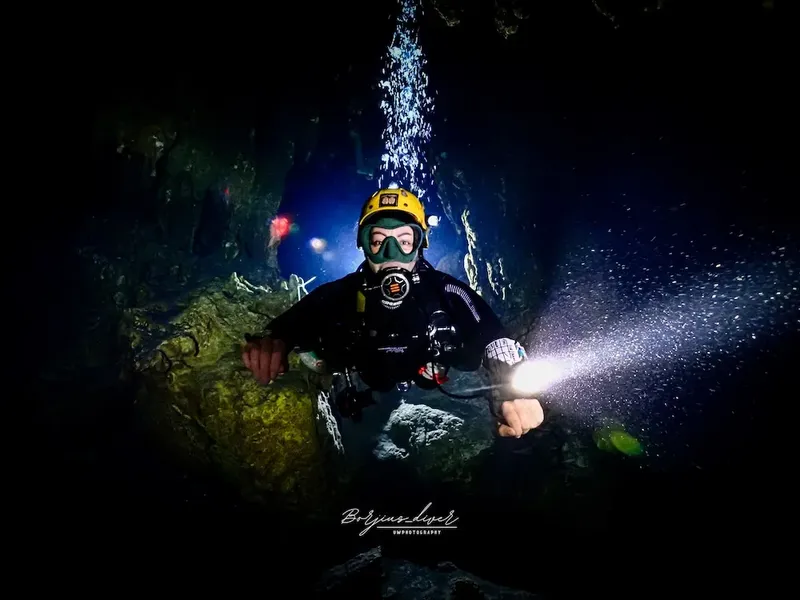 Plongeur éclairant une grotte sous-marine avec une lampe torche puissante