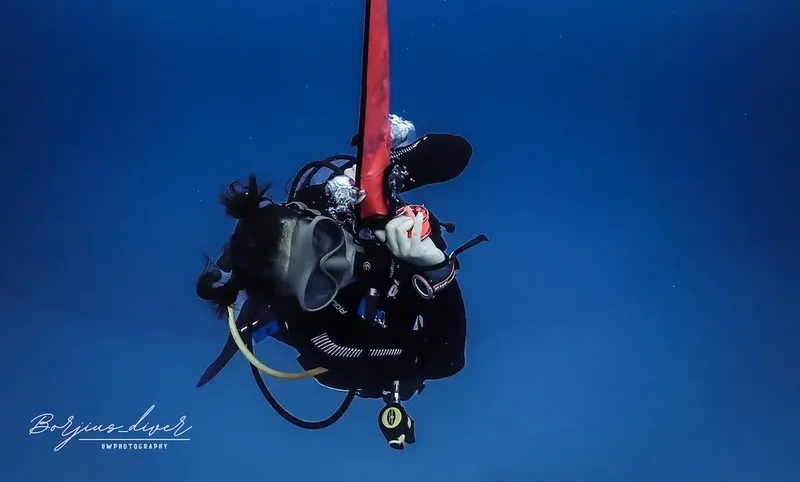 Plongeur en combinaison noire, flottant verticalement dans l'eau bleue