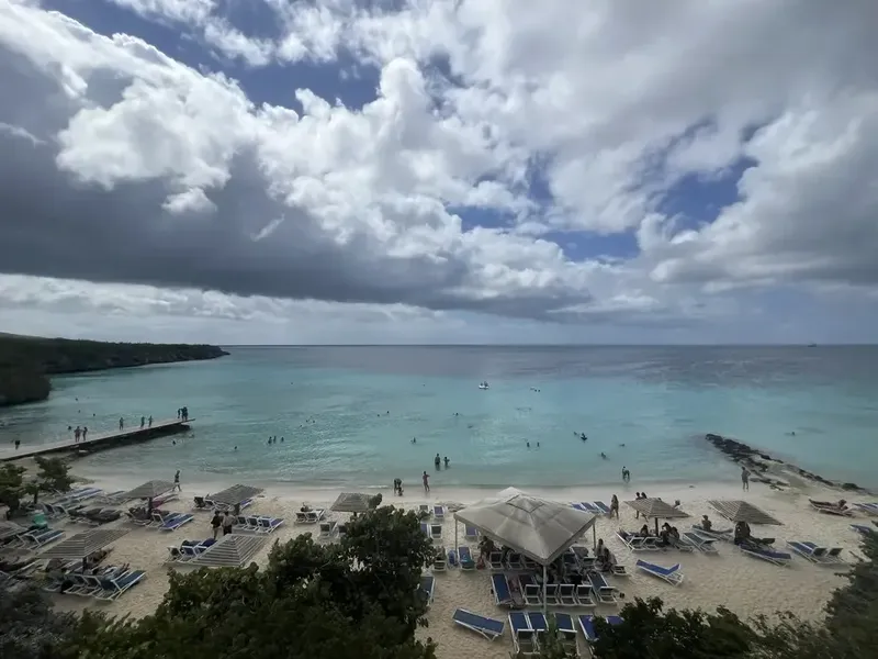 Plage avec des baigneurs, transats et parasols sous un ciel nuageux