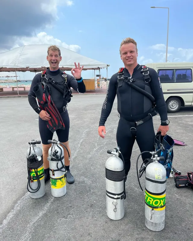 Deux plongeurs en combinaison, équipés, souriants et prêts à plonger