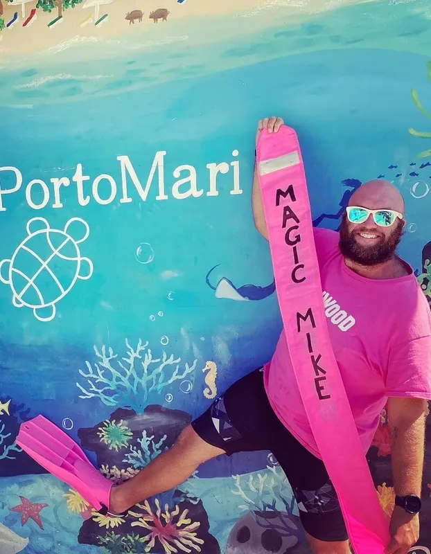 Homme souriant avec palmes devant une fresque marine colorée