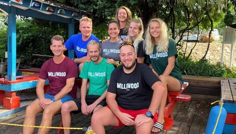 Groupe de personnes souriantes posant en extérieur, portant des t-shirts