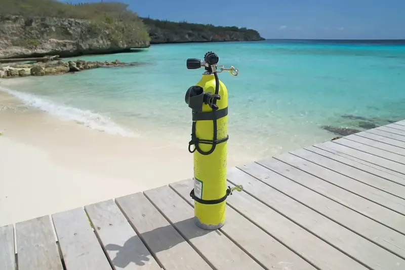 Bouteille de plongée jaune sur un ponton en bois face à la mer
