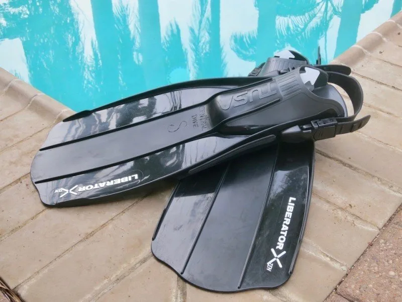 Paire de palmes de plongée noires et grises sur carrelage turquoise