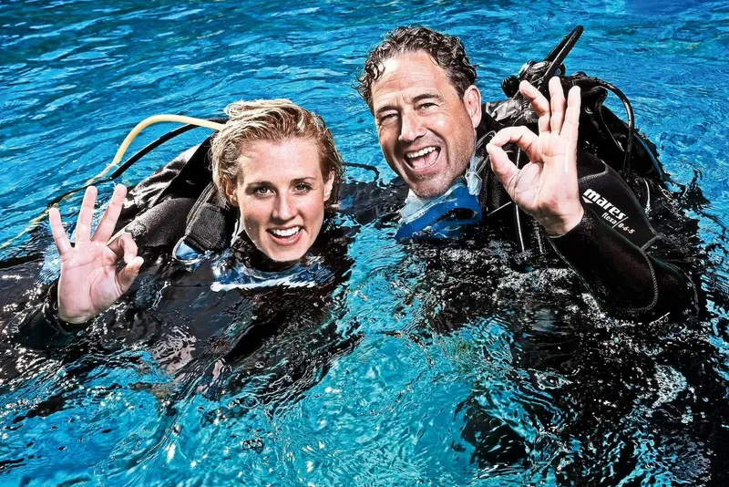 Deux plongeurs souriants font un signe OK sous l'eau bleue