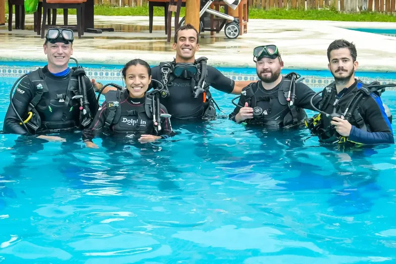 Groupe de plongeurs souriants en combinaison dans une piscine bleue