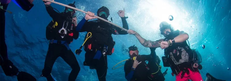 Plongeurs en formation manipulant une corde sous l'eau, lumière vive