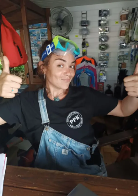 Femme souriante avec masque de plongée, pouces levés, dans un local