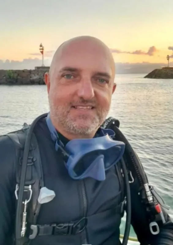 Plongeur souriant avec masque et équipement sur un bateau
