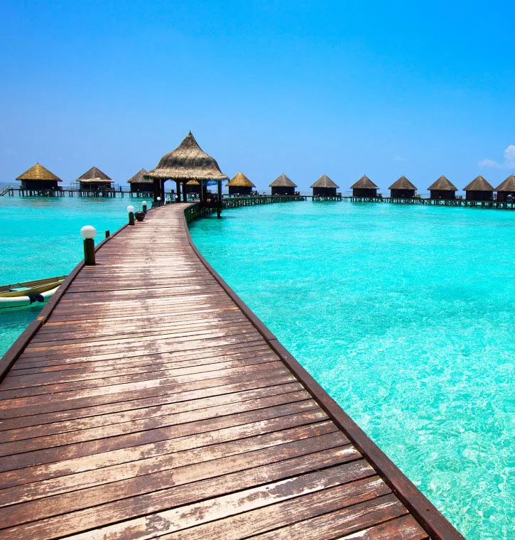Ponton en bois menant à des bungalows sur pilotis dans l'eau turquoise
