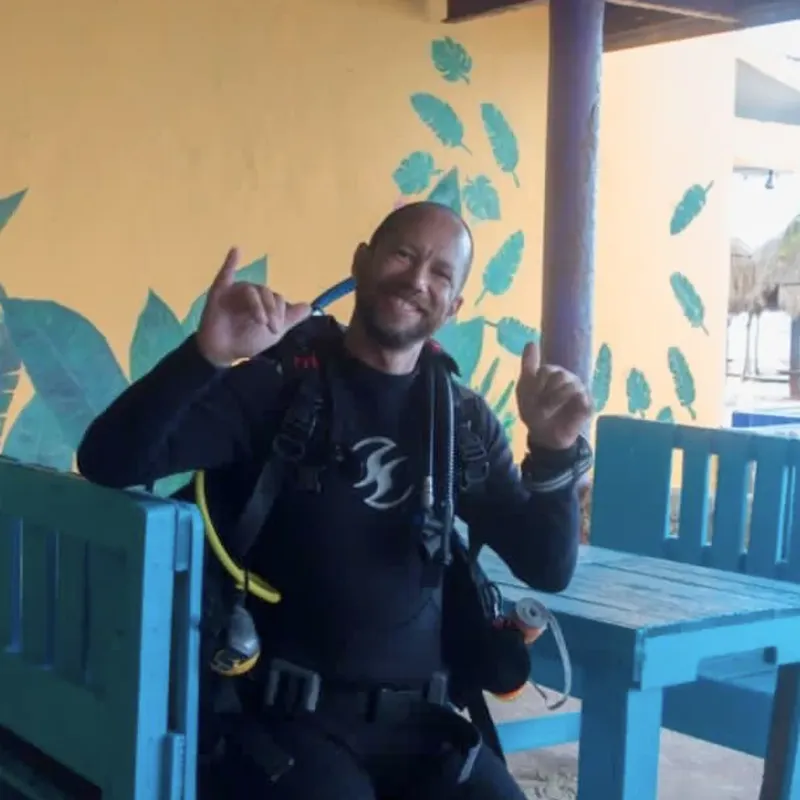 Plongeur souriant avec son équipement complet, assis à une table