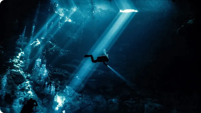 Plongeur silhouette sombre explorant un environnement sous-marin éclairé par des rayons