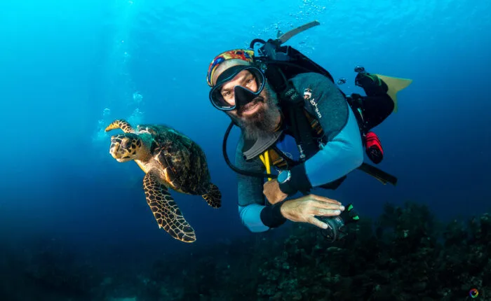 Plongeur souriant nage avec une tortue marine dans l'eau bleue