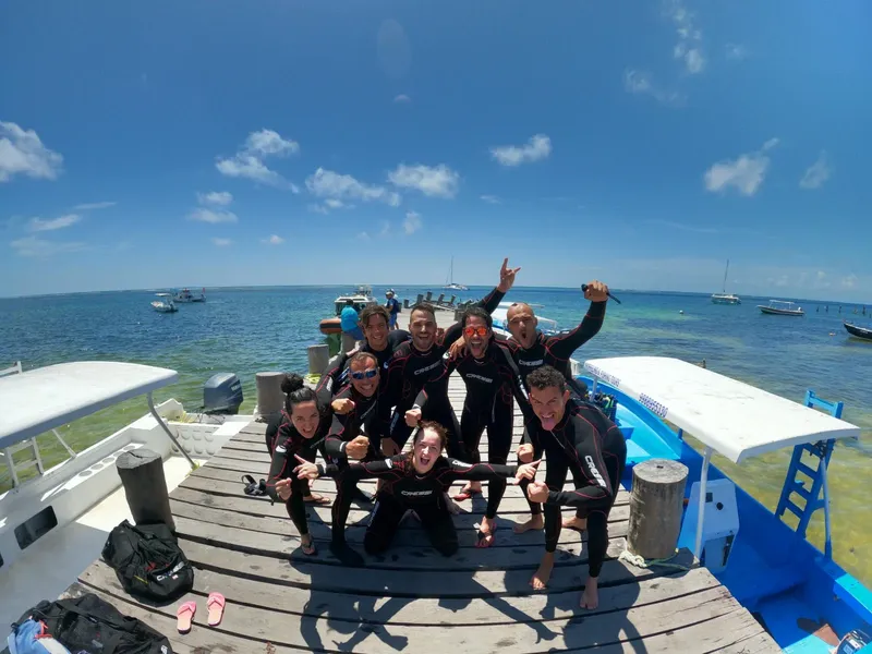 Groupe de plongeurs souriants sur un ponton ensoleillé au large