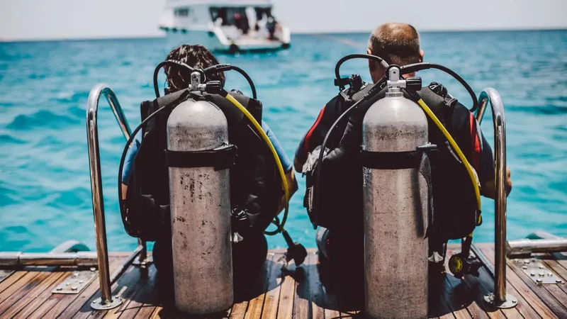Deux plongeurs équipés se préparent à entrer dans la mer