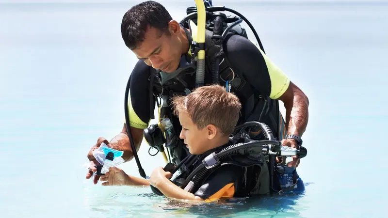 Moniteur et jeune plongeur vérifient l'équipement avant l'immersion