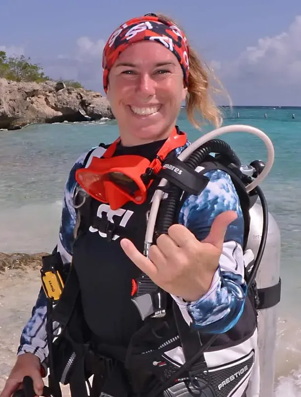 Plongeuse souriante avec son équipement complet sur une plage ensoleillée