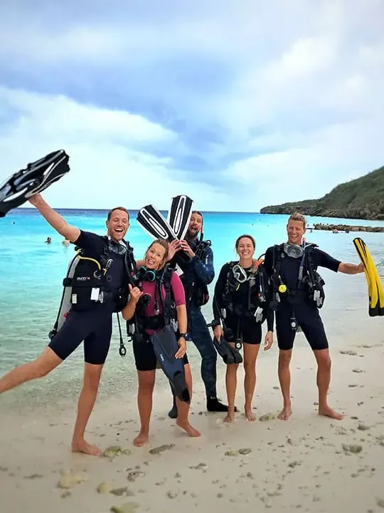 Groupe de plongeurs souriants sur une plage ensoleillée avec palmes