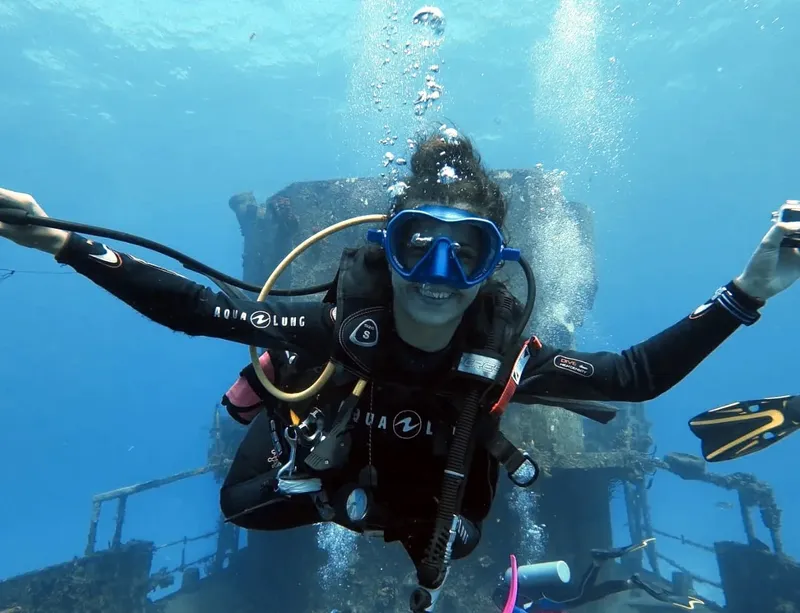 Plongeuse souriante filmant avec un appareil photo sous-marin