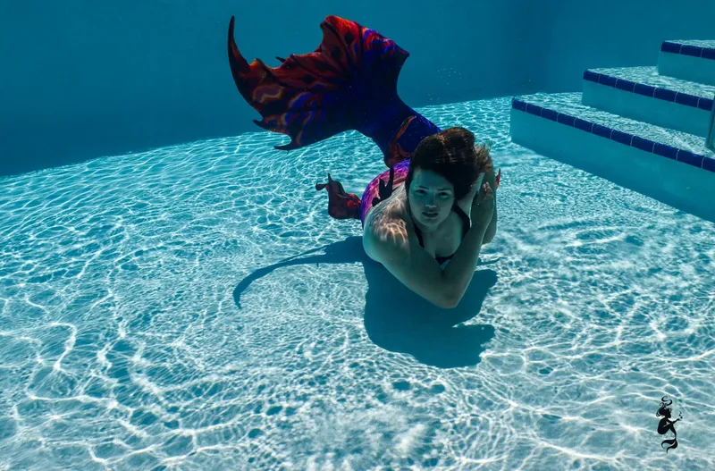 Femme nageant avec une queue de sirène dans une piscine claire