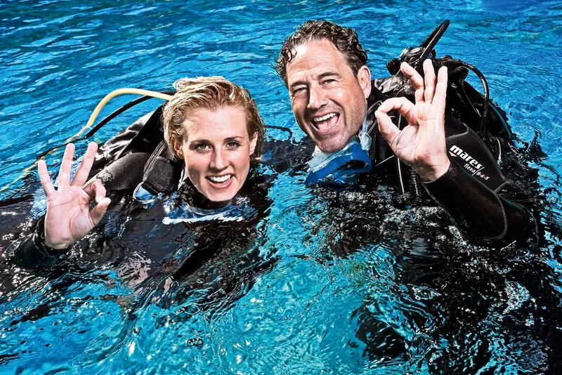Deux plongeurs souriants font un signe OK sous l'eau