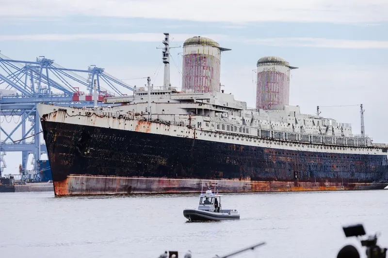 Grand paquebot rouillé amarré au port avec un bateau pneumatique