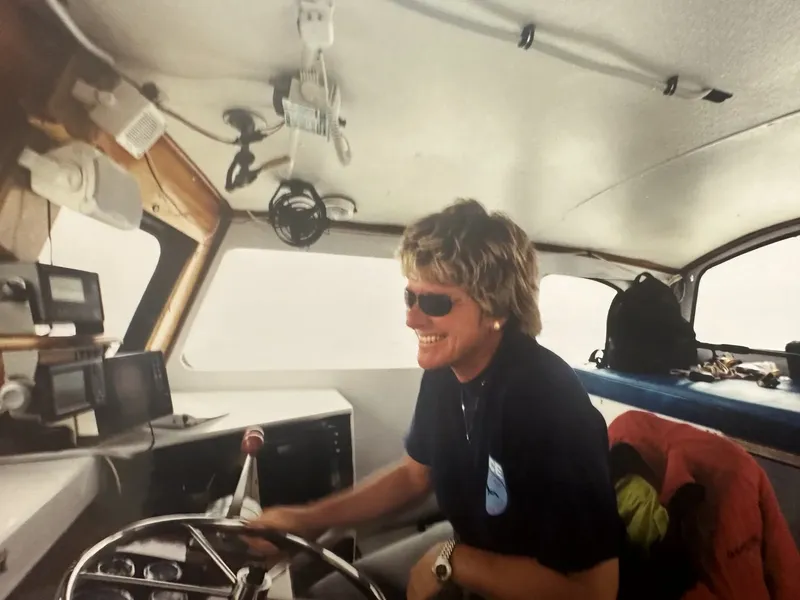 Homme souriant aux lunettes de soleil tient le volant d'un bateau