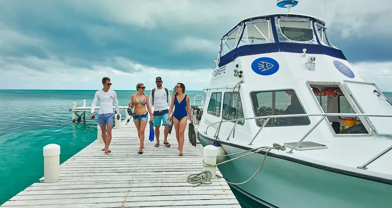 Quatre personnes marchent sur un ponton vers un bateau de plongée