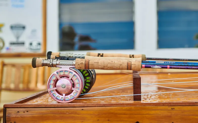 Canne à pêche à mouche et moulinet roses sur une table en bois