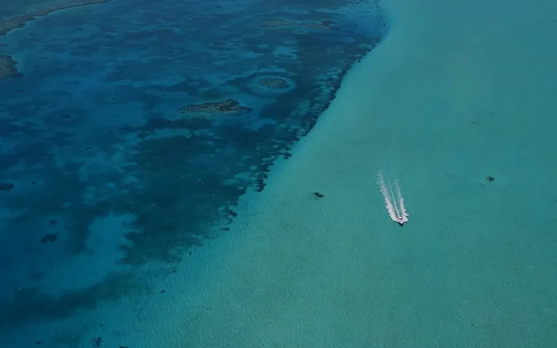 Vue aérienne d'un bateau naviguant sur une eau turquoise et claire