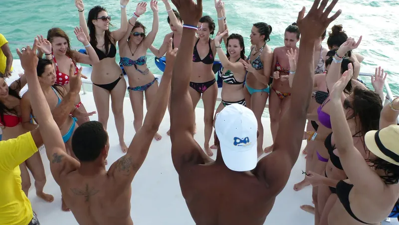 Groupe de personnes sur un bateau, bras levés, ambiance festive