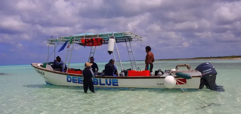 Bateau de plongée avec des personnes et du matériel dans l'eau turquoise