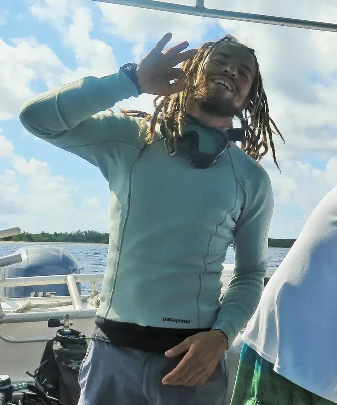 Un homme souriant sur un bateau de plongée, avec équipement