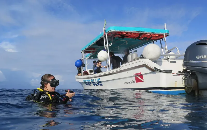 Plongeuse en surface près d'un bateau de plongée avec des passagers