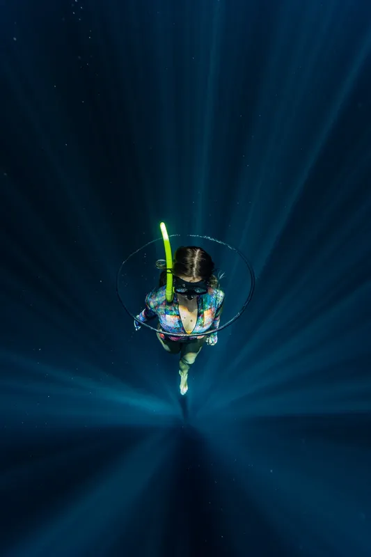 Apnée : une plongeuse évolue verticalement dans une eau bleu profond