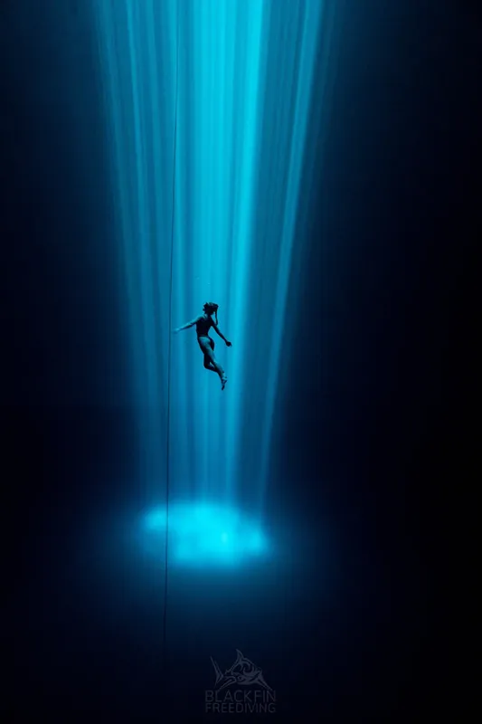 Apnée en profondeur, une nageuse descend le long d'un câble bleu