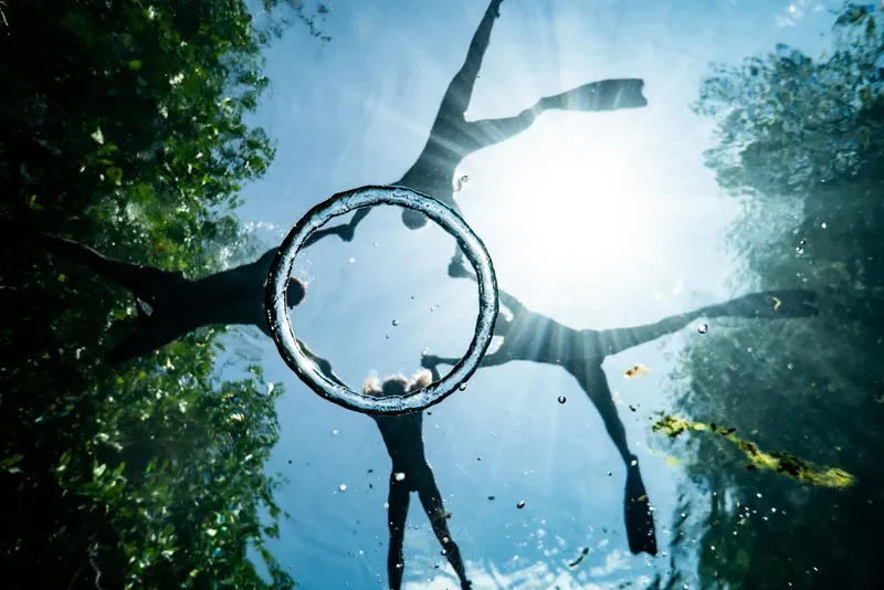 Plongeur vu d'en bas, jambes tendues, lumière vive sous-marine