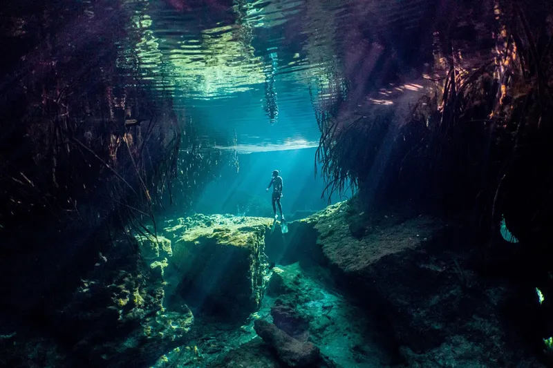 Plongeur solitaire explore une grotte sous-marine éclairée par des rayons