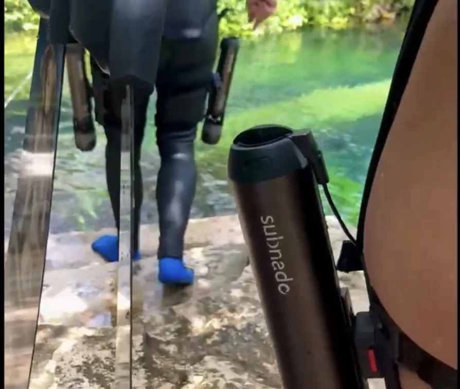 Plongeur en combinaison noire marchant dans une eau trouble et claire
