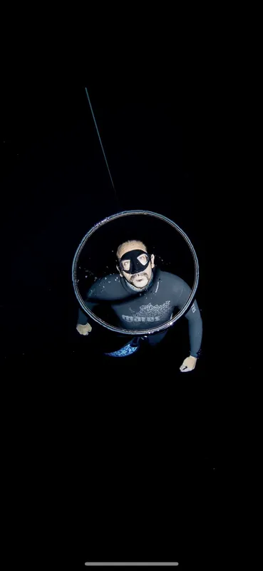 Apnéiste regardant la caméra à travers un cercle sous-marin