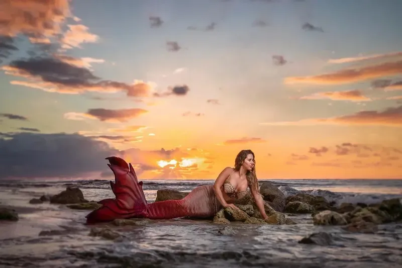 Femme avec queue de sirène au coucher du soleil sur des rochers