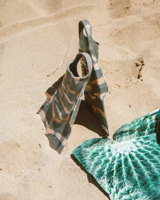 Palmes de plongée et serviette colorée sur sable clair ensoleillé