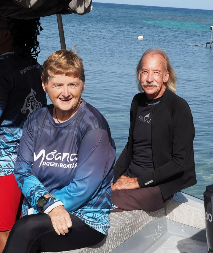 Deux personnes souriantes sur un bateau en mer, temps ensoleillé