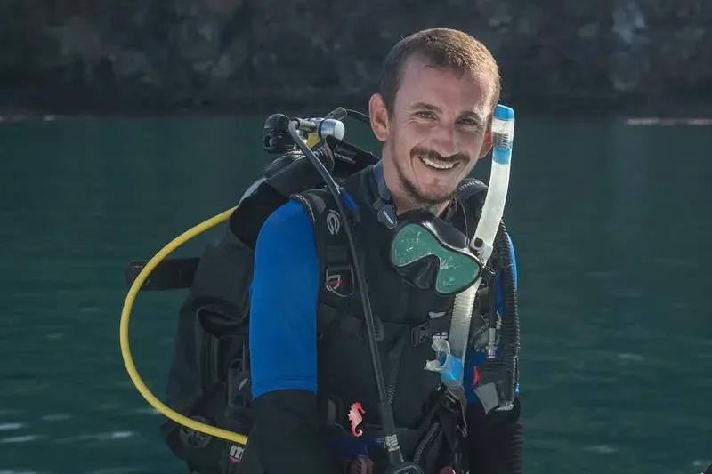 Plongeur souriant équipé de son matériel prêt à plonger en mer