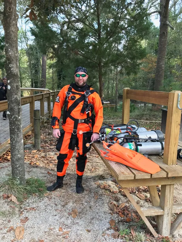 Plongeur en combinaison orange complet, debout avec son équipement