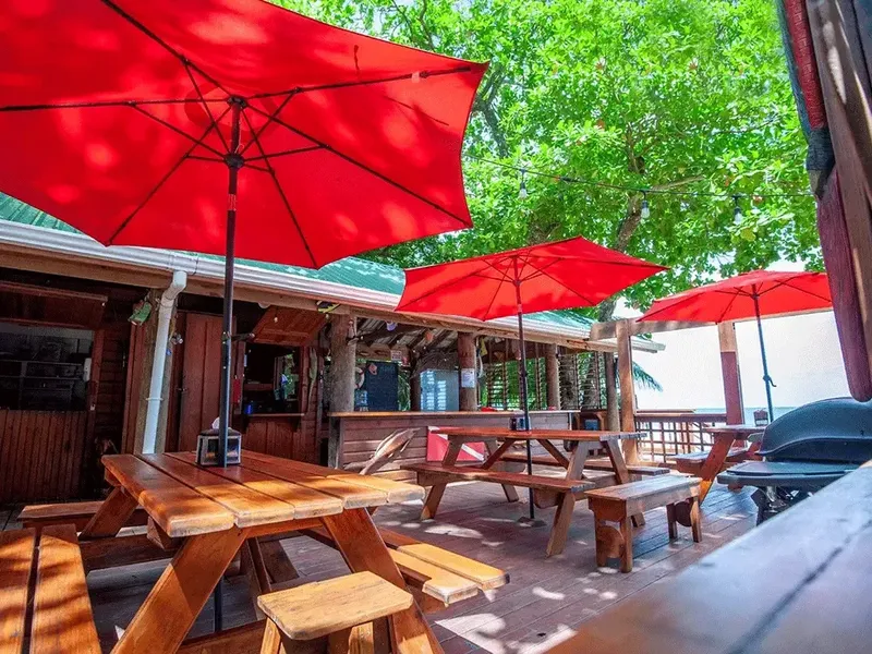Terrasse ombragée avec tables en bois et parasols rouges ouverts