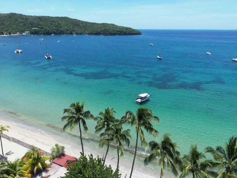 Vue aérienne d'une plage tropicale avec des bateaux en mer turquoise