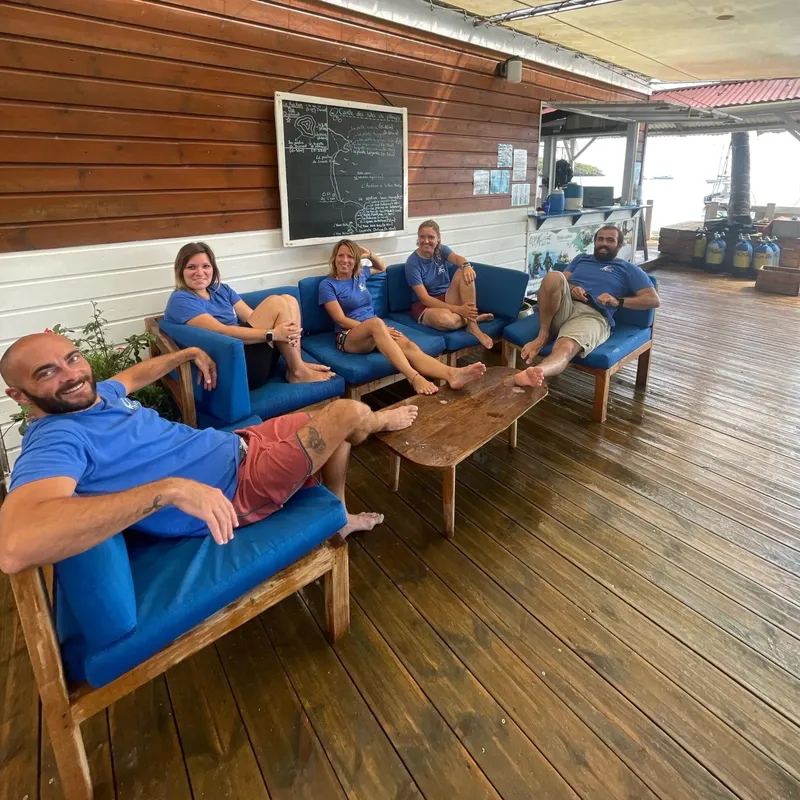 Groupe de personnes assises et souriantes sur une terrasse en bois