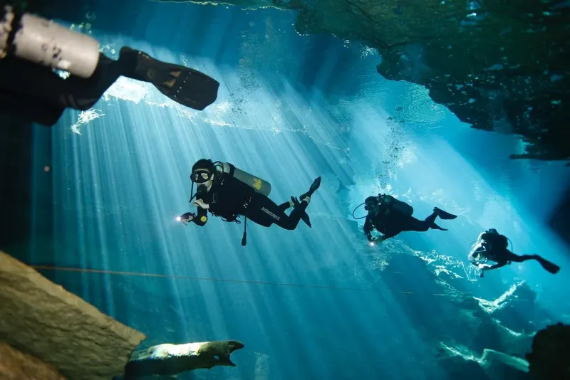 Plongeurs explorant une grotte sous-marine avec des rayons de lumière